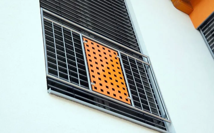 Französisches Geländer vor einer Fenstertür mit orangem Lochblech-Element