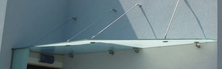 Glasvordach über einem Eingang, gehalten von Punkthaltern und Streben