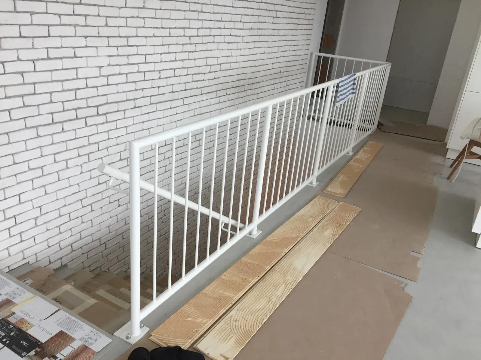 Weißes Stabgeländer entlang einer Rampe vor einer weißen Klinkerwand