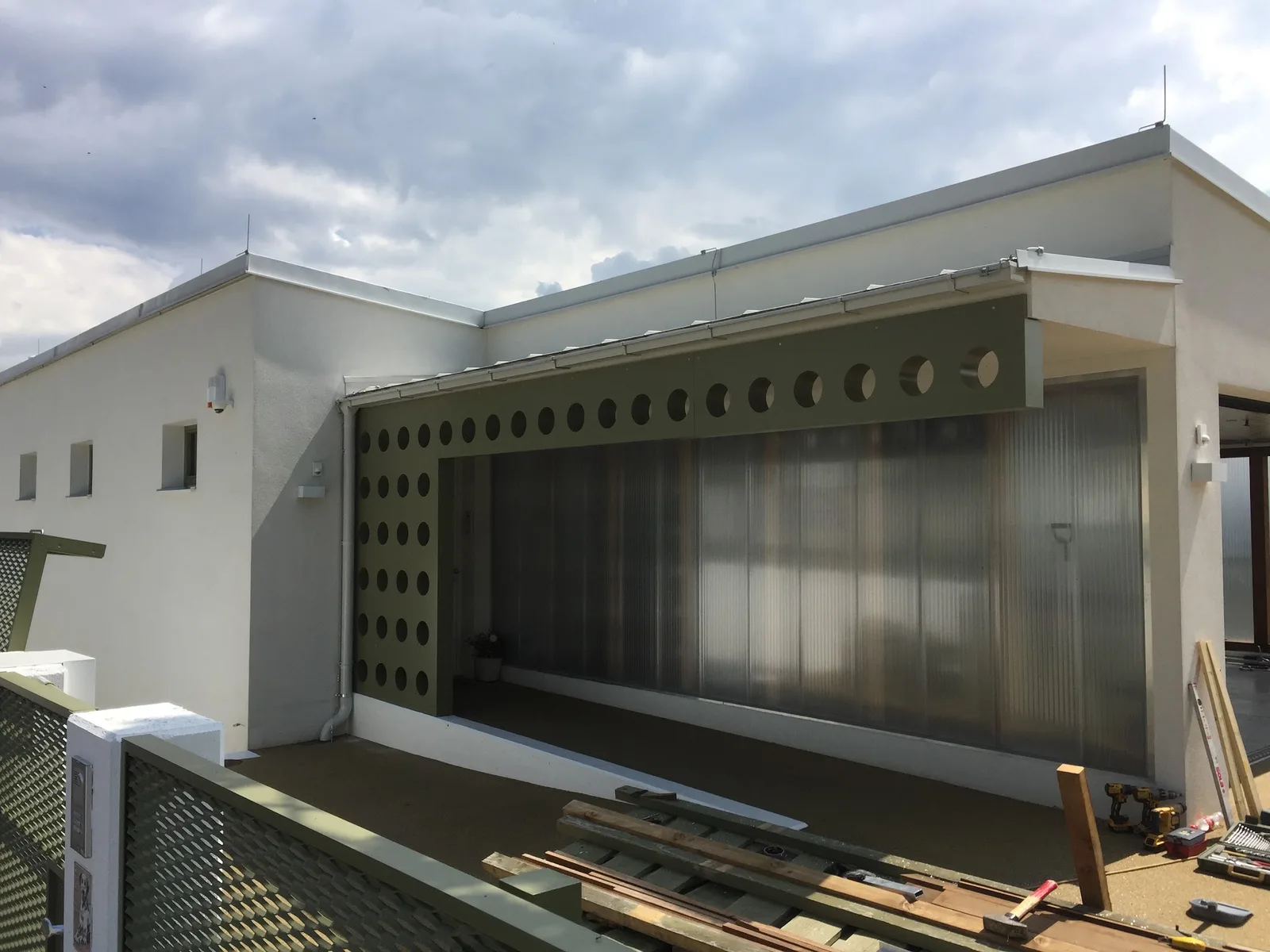 Carport an einem Flachdachhaus mit Blende aus Lochblech und runden Ausschnitten